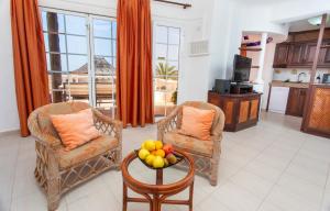una sala de estar con 2 sillas y una mesa con fruta. en Altamar 28 with terrace&pool By CanariasGetaway, en Playa del Águila