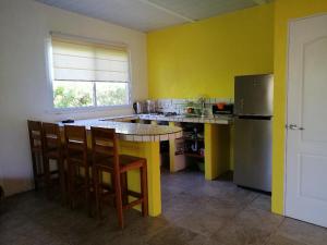 uma cozinha com paredes amarelas, um frigorífico e cadeiras em CASITA COLIBRIS em Copecito