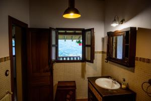 baño con lavabo y ventana en La Xamoca Apartamentos Rurales en Campiellos