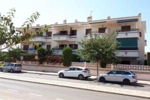 drie auto's geparkeerd voor een gebouw bij Apartment with private balcony in San Javier