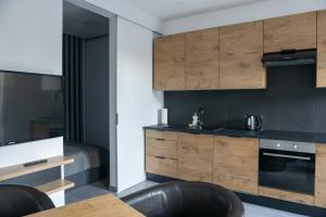 una cocina con armarios de madera, mesa y sillas en Apartamenty Dworcowa 45 en Gliwice