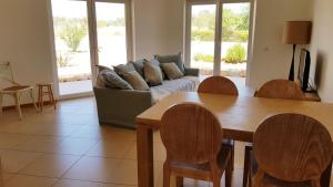uma sala de estar com um sofá, uma mesa e cadeiras em T2 Cabanas Gardens piscina e praia em Cabanas de Tavira