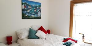 um quarto com uma cama branca e almofadas coloridas em Ginger's em Stirling