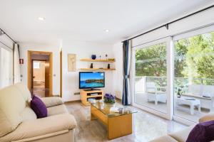 a living room with a couch and a tv at Villa MARTINA in Cala en Forcat
