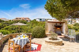 a patio with a table and chairs and a fireplace at Villa MARTINA in Cala en Forcat