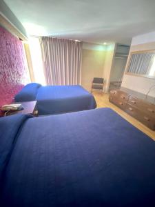 Habitación de hotel con 2 camas con sábanas azules en Hotel Zacatecas Courts, en Zacatecas
