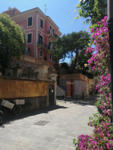 a street with a pink building and purple flowers at La casa del girasole in Sestri Levante