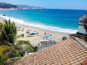 a beach with umbrellas and boats on the sand at Casa de las Olas in Mazunte