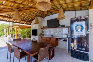 a dining room with a wooden table and a television at Village Reserva das Ilhas - Itacimirim in Itacimirim
