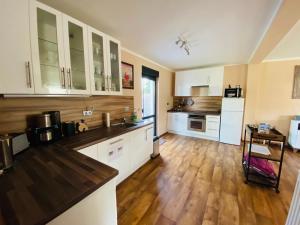 a kitchen with white cabinets and a wooden floor at Großzügiges Ferienhaus am Senftenberger See mit 2 Terrassen in Senftenberg +6 photos