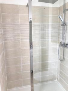 une douche avec une porte vitrée dans une salle de bain dans l'établissement Maison Cosy avec terrasse à 10 minutes du centre ville, à La Rochelle