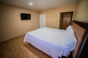 California Comfort & Suites في Los Algodones: غرفة نوم بسرير ابيض وتلفزيون بشاشة مسطحة