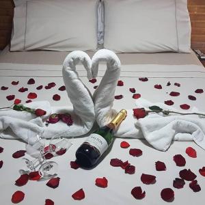 a bed with two swans and a bottle of champagne at Pousada Recanto das Águas in Lumiar