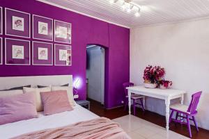 ein lila Schlafzimmer mit einem Bett und einem Tisch in der Unterkunft Villa Bonaccorso - antica e maestosa villa con piscina ai piedi dell'Etna in Viagrande