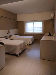 ein Hotelzimmer mit 2 Betten und einem Fenster in der Unterkunft Hotel Manta in Pelotas