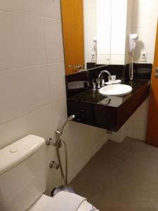 a bathroom with a sink and a toilet and a mirror at Hotel Manta in Pelotas