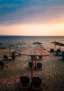 una spiaggia con sedie e ombrelloni e l'oceano di Mr & Mrs K Bianco a Potos