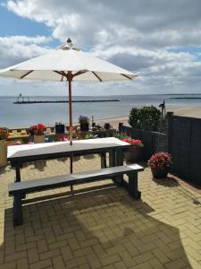 a picnic table with an umbrella on the beach at Captains Lodge in Newbiggin-by-the-Sea