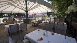 un restaurante con mesas, sillas y sombrillas blancas en Hotel LukasMayr, en Bruck an der Großglocknerstraße