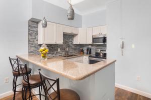 a kitchen with white cabinets and a counter with stools at The BoatHouse in Marco Island