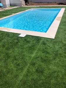 a swimming pool with green grass next to a house at Casa da Azenha Castellvm in Alcabideque