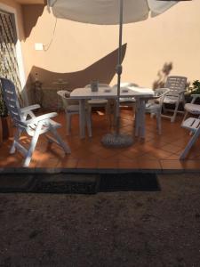 un tavolo con sedie e un ombrellone su un patio di Casa Maltinu a Santa Teresa di Gallura