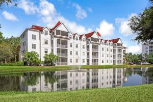 un grand bâtiment blanc avec un étang en face dans l'établissement Hilton Vacation Club Grand Beach Orlando, à Orlando