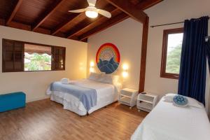 een slaapkamer met 2 bedden en een plafondventilator bij Ubatuba Ecologic Pousada in Ubatuba