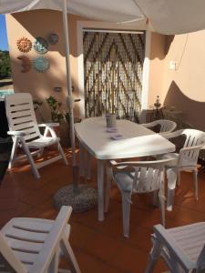 uma mesa branca e cadeiras com um guarda-sol num quarto em Casa Maltinu em Santa Teresa Gallura
