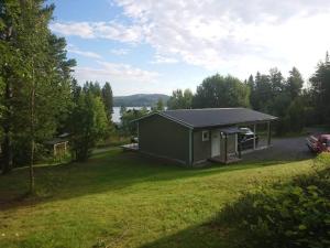 ein kleines grünes Gebäude in einem Hof mit einem Feld in der Unterkunft Elvis Stuga in Östersund