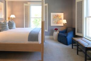 a bedroom with a large bed and a blue chair at Inns of Aurora Resort & Spa in Aurora
