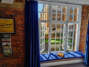 a window with blue curtains next to a brick building at Cocoa Isabella - River fronted with secure parking in York