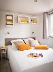 1 dormitorio con 1 cama blanca grande con almohadas de color naranja en Amelia Camping, en Amélie-les-Bains-Palalda