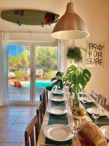 a dining room with a long table with chairs and a pool at Endless Summer Surf House in Aljezur