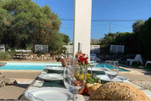 a table with plates and wine glasses next to a pool at Endless Summer Surf House in Aljezur