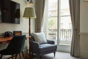 Habitación con silla, lámpara y ventana en Lime Tree Hotel, en Londres