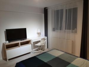 a bedroom with a tv and a bed with a desk at Light HOUSE in Cluj-Napoca