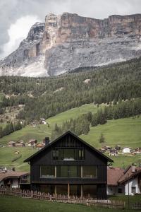 a black house with a mountain in the background at Larix Lodge in La Villa