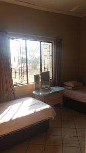 a bedroom with two beds and a window at Confortable farmhouse in Limpopo Province in Lephalale