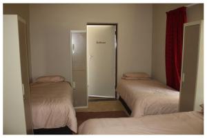 a room with three beds and a door to a closet at Confortable farmhouse in Limpopo Province in Lephalale +2 photos