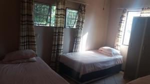 a bedroom with two beds and two windows at Homely room in peaceful and comfortable old farmhouse in Lephalale