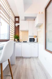 una cocina con armarios blancos y una silla blanca en Unique Hotel Apartments Rond Vechi en Iaşi