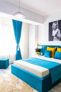 a bedroom with a large bed with blue and yellow pillows at Unique Hotel Apartments Rond Vechi in Iaşi
