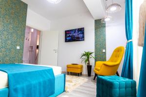 a hotel room with a bed and a yellow chair at Unique Hotel Apartments Rond Vechi in Iaşi