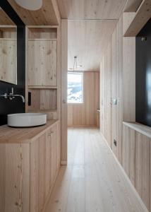 bagno con pareti in legno, lavandino e finestra di Larix Lodge a La Villa