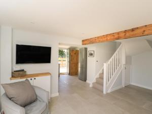 a living room with a tv on the wall and a chair at Kingfisher, 2 The Old Stables in Witney