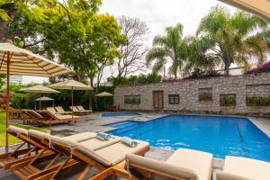 una piscina con tumbonas y sombrillas en Hotel Flamingo Inn en Querétaro