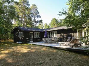 a black cabin with a porch and a patio at Holiday home Fårevejle XII in Fårevejle