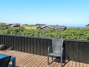a chair sitting on a deck with the ocean in the background at 8 person holiday home in Hj rring in Lønstrup