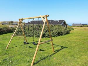 a swing set in a yard with a grass field at 8 person holiday home in Hj rring in Lønstrup